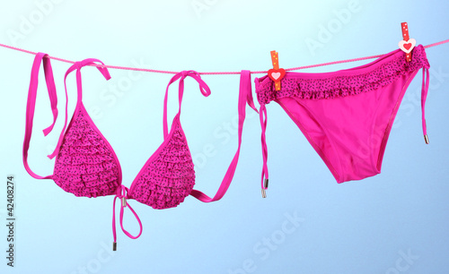 Foto: Women's swimsuit hanging on a rope on blue background Women's swimsuit hanging on a rope on blue background