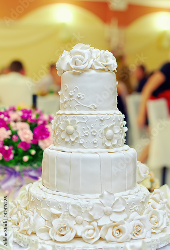 Photo: white floral wedding cake on restaurant interior background white floral wedding cake on restaurant interior background