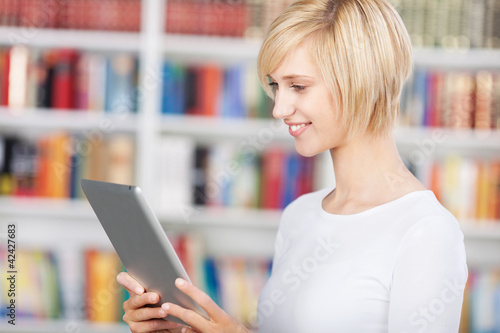 Foto: junge frau mit tablet-pc in der bibliothek junge frau mit tablet-pc in der bibliothek