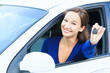 Pretty female driver in a white car showing the car key