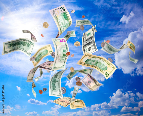 Photo: American dollars banknotes and coins falling from blue sky American dollars banknotes and coins falling from blue sky