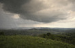 landscape with rain and dramatic clouds over hills