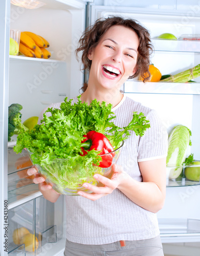 Photo: Beautiful Young Woman near the Refrigerator with healthy food Beautiful Young Woman near the Refrigerator with healthy food