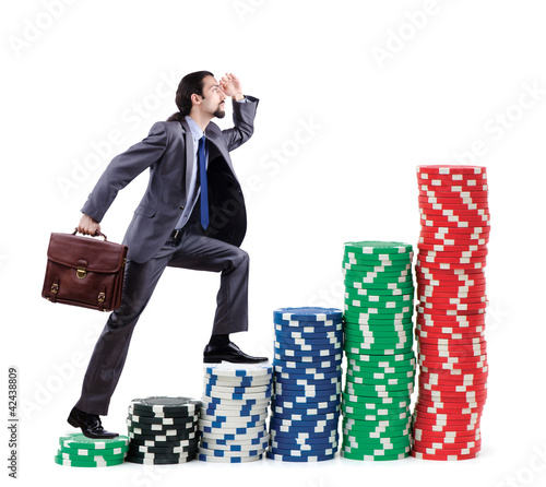 Foto: Businessman climbing stacks of casino chips Businessman climbing stacks of casino chips