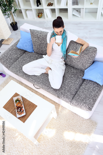 Photo: Relaxation woman with tea and book in living room Relaxation woman with tea and book in living room