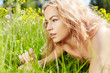 beautiful blond girl on green field with flowers
