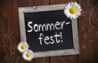 Kreidetafel mit Sommerfest auf Holzwand und Blüten