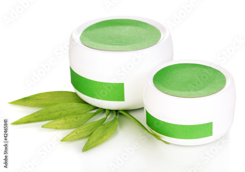 Foto: Jars of cream with green leaves isolated on white Jars of cream with green leaves isolated on white