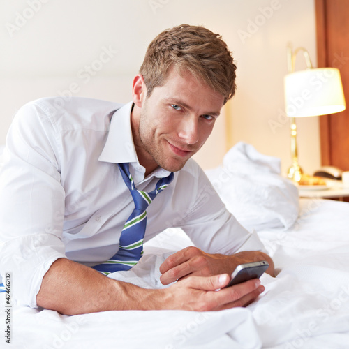 Foto: Mann liegt mit Smartphone im Bett Mann liegt mit Smartphone im Bett