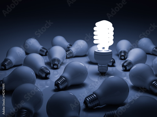 Photo: Lit energy saving lightbulb amongst unlit incandescent bulbs Lit energy saving lightbulb amongst unlit incandescent bulbs