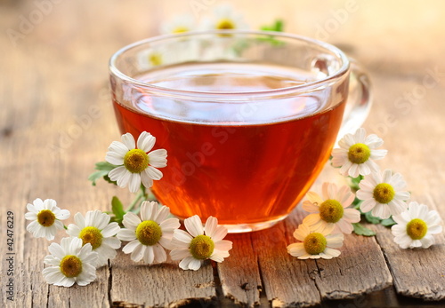 Foto: cup of tea and chamomile flowers on a wooden table cup of tea and chamomile flowers on a wooden table