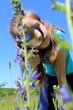 Little girl using magnifying glass examining field flowers