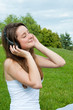 Girl in headphones listens to music in the park.