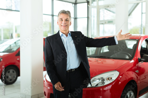 Photo: Älterer Mann oder Verkäufer mit Auto im Autohaus Älterer Mann oder Verkäufer mit Auto im Autohaus