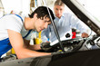 Kunde und Mechaniker an Auto schauen unter Haube