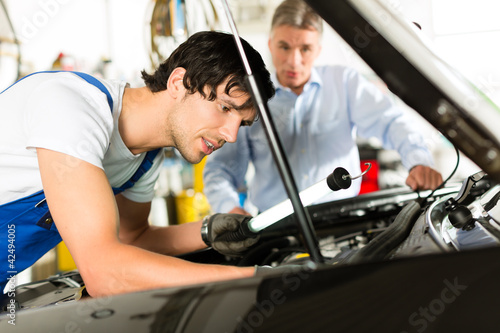 Photo: Kunde und Mechaniker an Auto schauen unter Haube Kunde und Mechaniker an Auto schauen unter Haube