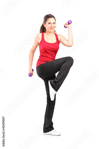 Photo: Full length portrait of a smiling teenager lifting up a dumbbell Full length portrait of a smiling teenager lifting up a dumbbell