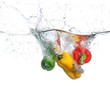 Three peppers falling into water, over white background