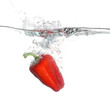 Red pepper falling into water over white background
