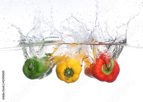 Photo: Three peppers falling into water, over white background Three peppers falling into water, over white background