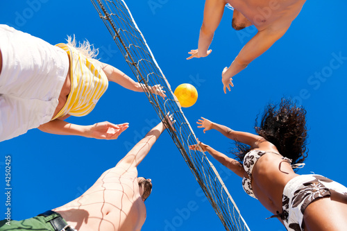 Foto: Friends playing beach volleyball Friends playing beach volleyball