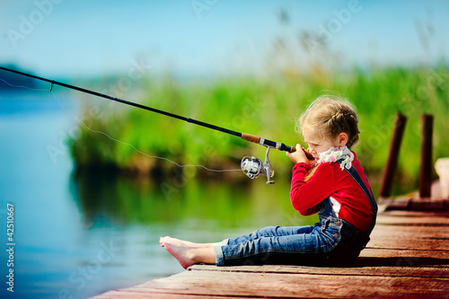 Photo: little girl fishing from wooden dock on lake little girl fishing from wooden dock on lake