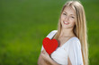 Photo: Young woman holding heart shape, on grass background Young woman holding heart shape, on grass background