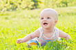 Happy laughing baby sitting on the grass