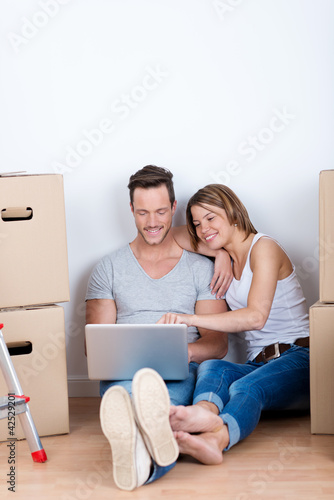 Foto: paar mit laptop sitzt zwischen kartons paar mit laptop sitzt zwischen kartons