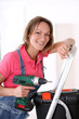 Woman standing on scale with electric drill