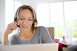 Foto: Portrait of woman with headset in front of laptop Portrait of woman with headset in front of laptop