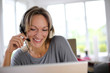 Foto: Portrait of woman with headset in front of laptop Portrait of woman with headset in front of laptop