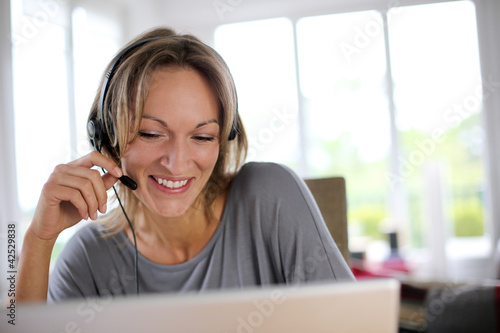 Foto: Portrait of woman with headset in front of laptop Portrait of woman with headset in front of laptop