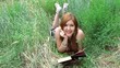 Portrait of a young woman reading book outdoors laying on grass