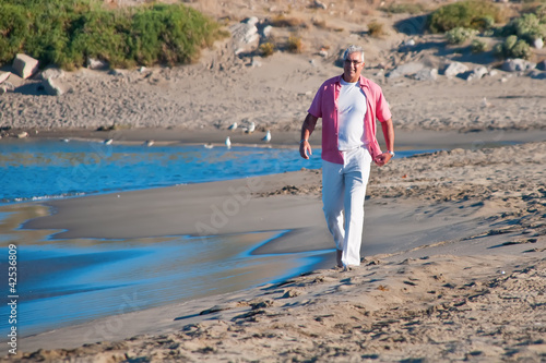 Photo: Happy mature man walking on the beach Happy mature man walking on the beach