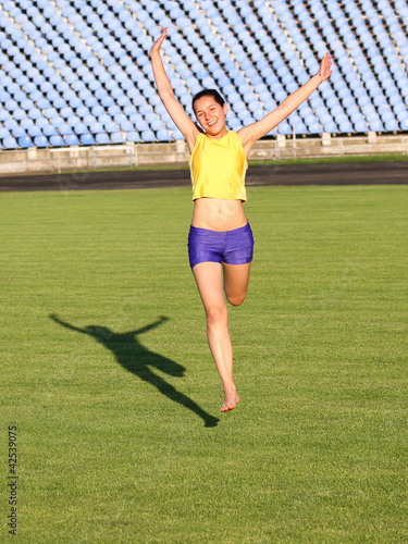 Photo: Beautiful teenage sport girl running on the grass. Beautiful teenage sport girl running on the grass.