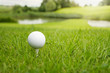 Golf ball on a tee against the golf course with copy space