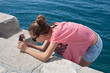 Foto: Teenage girl taking photos by the sea Teenage girl taking photos by the sea