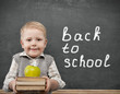 Foto: Cheerful smiling child with a book and apples stands at the blac Cheerful smiling child with a book and apples stands at the blac