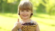 Happy child with a basket of fruit cherries. Thumbs up. Ok