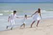 Mother, Father and Child Family Running Having Fun At Beach