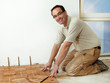 Foto: Smiling carpenter at work is fitting wood parquet on the floor Smiling carpenter at work is fitting wood parquet on the floor