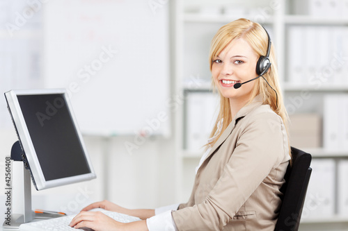 Foto: blonde frau mit headset und computer im büro blonde frau mit headset und computer im büro