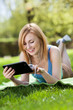 Woman lying on grass with digital tablet