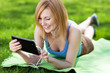 Woman lying on grass with digital tablet