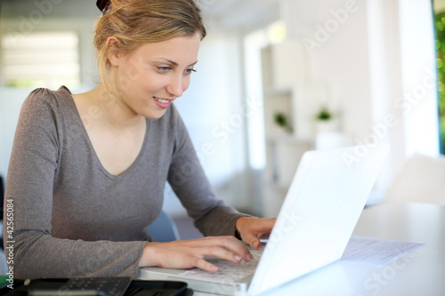 Photo: Beautiful young woman studying at home on laptop Beautiful young woman studying at home on laptop