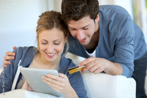 Photo: Young couple at home buying on internet Young couple at home buying on internet