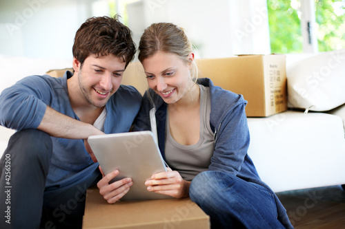 Photo: Young couple using tablet to find transport company Young couple using tablet to find transport company