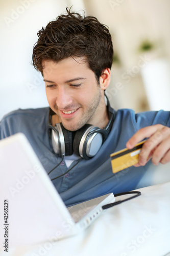 Photo: Young man buying music on internet with tablet Young man buying music on internet with tablet