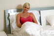 Foto: Frau sitzt im Bett und lacht Frau sitzt im Bett und lacht